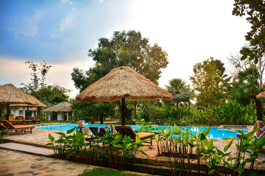 a pool with a thatched umbrella and chairs